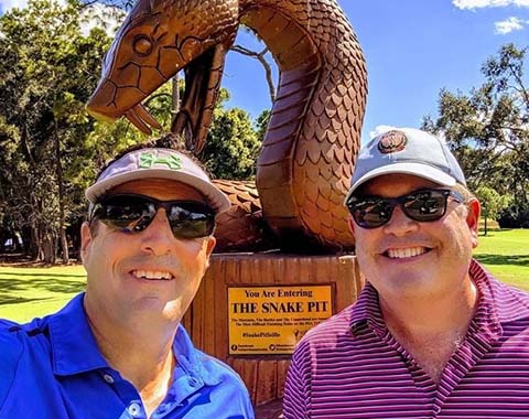 Two guys posing in front of a statue