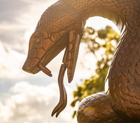 A statue of a snake with the golf course in the background